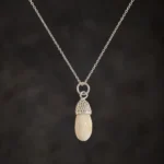 Colgante de colmillo de ciervo común con casquillo granulado y cadena de plata de ley 925 sobre fondo oscuro