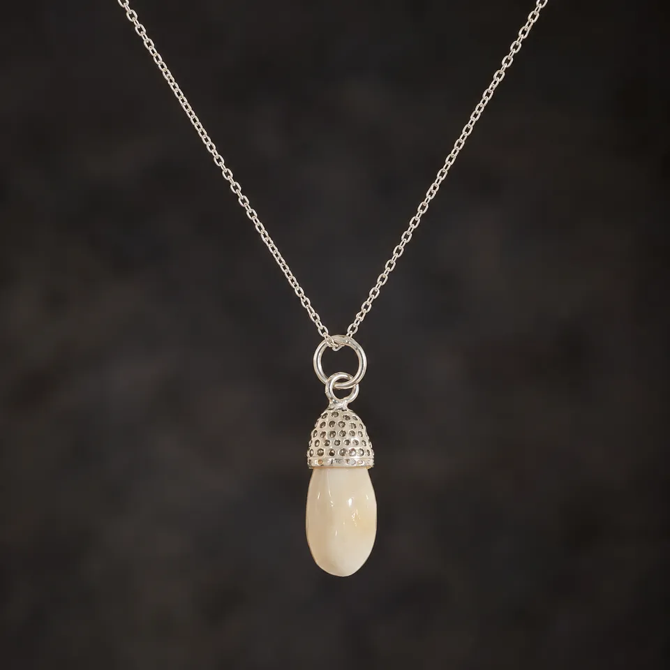 Colgante de colmillo de ciervo común con casquillo granulado y cadena de plata de ley 925 sobre fondo oscuro
