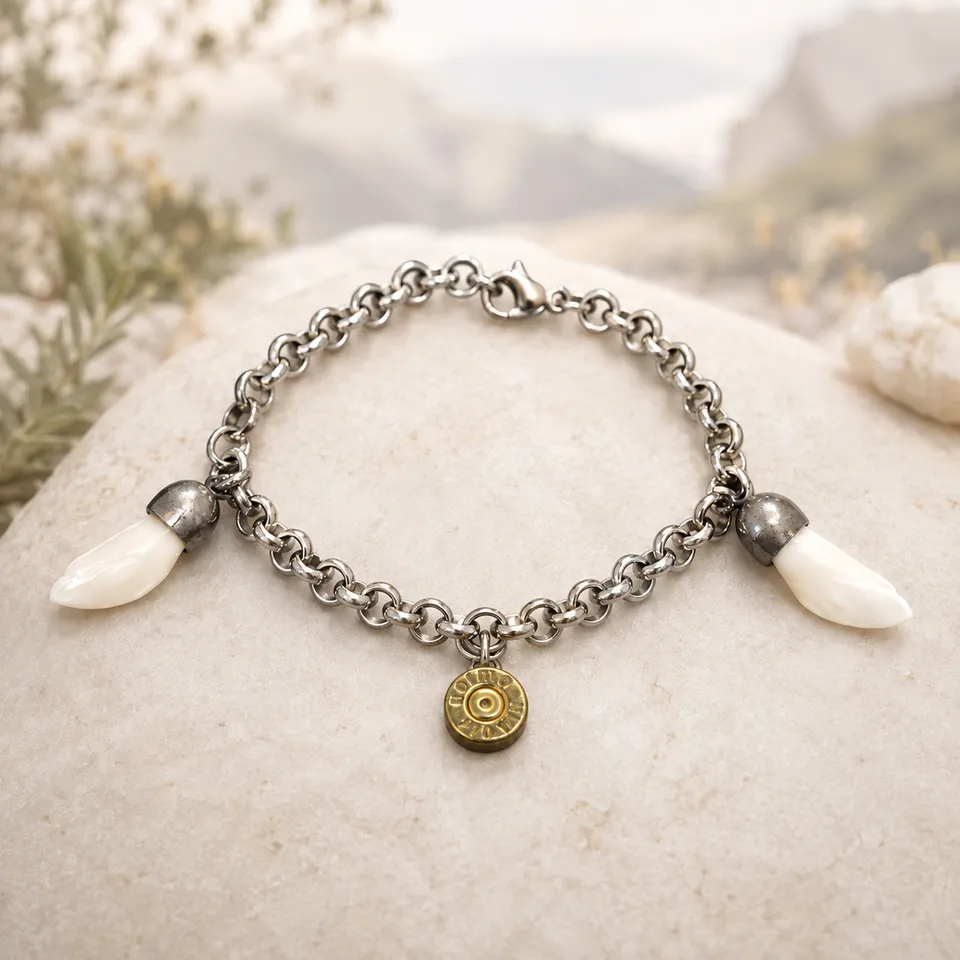 Pulsera de acero con dientes naturales de jabalí y colgante de bala sobre fondo claro inspirado en la Sierra de Cazorla