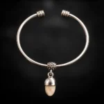 Pulsera rígida de alpaca con colmillo natural de ciervo sobre fondo negro difuminado