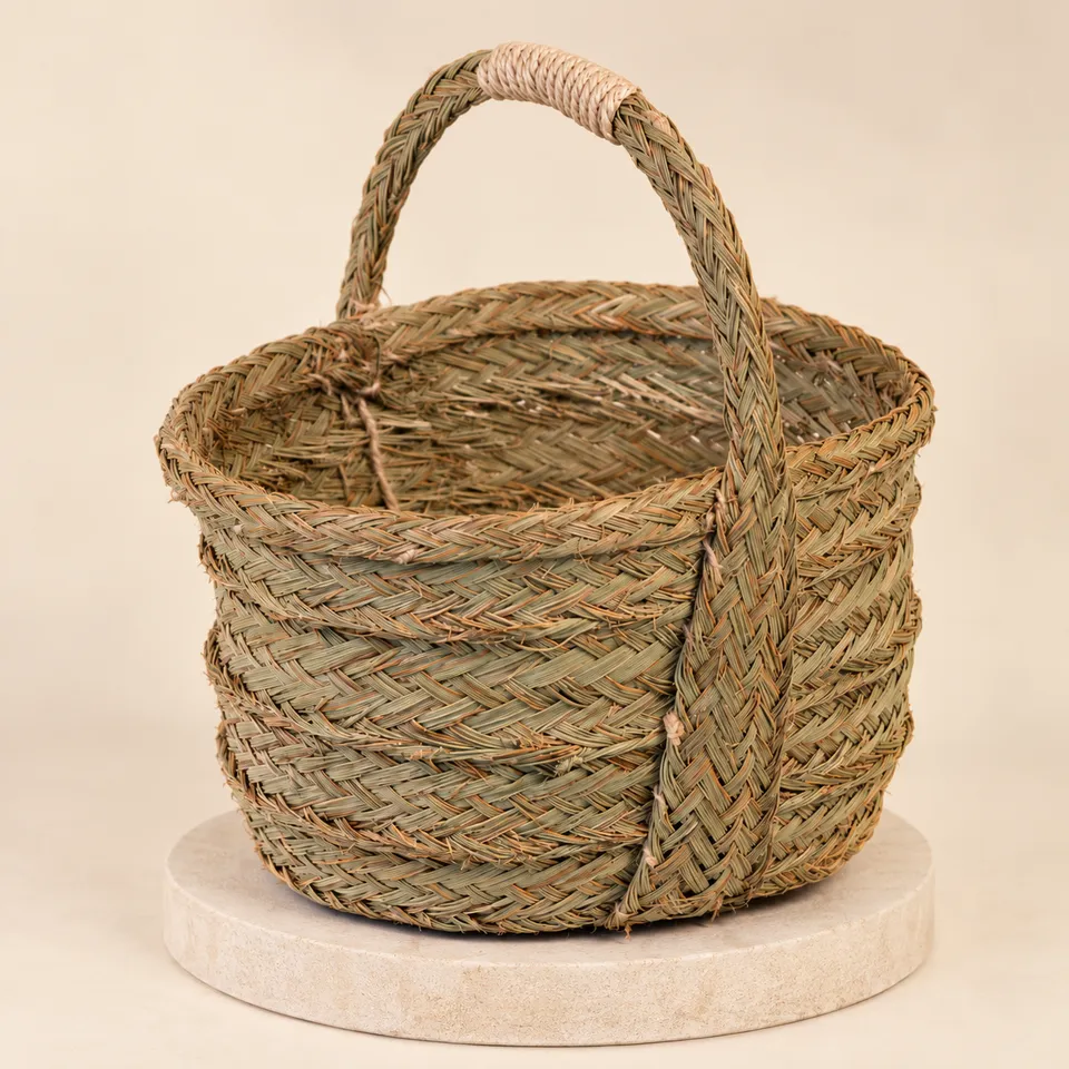 Cesta bolso artesanal de esparto con un asa sobre plataforma y fondo cálido
